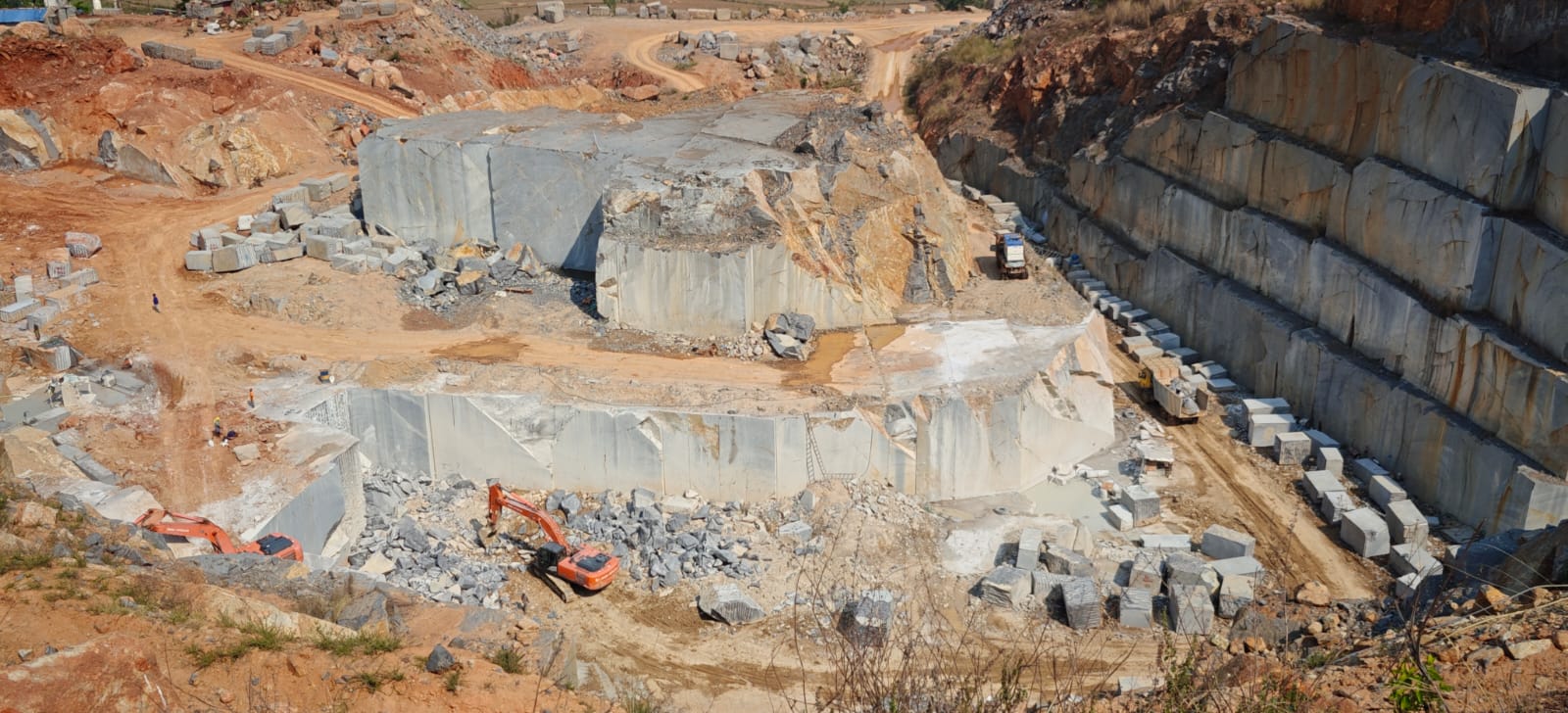 Stepped benches of blue-grey granite being extracted at the quarry